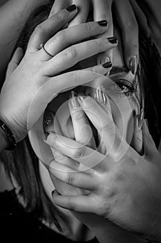 Black and white portrait of a young woman with her face covered with hands, concept for showing the anxieties and fears of women photo