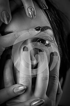 Black and white portrait of a young woman with her face covered with hands, concept for showing the anxieties and fears of women