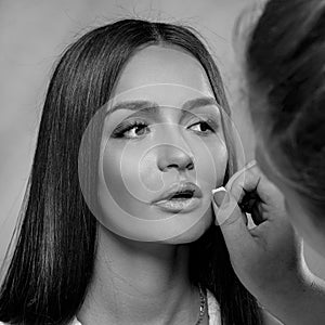 Black and white portrait young woman. Makeup artist corrects the model`s makeup