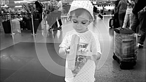 Black and white protrait of cute toddler boy playing with toy airplane in airport terminal