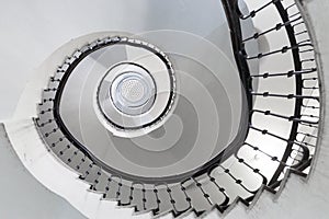 Black and white round spiral staircase with black railings with patterns top view