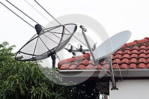 Black and white satellite dish and tv antenna at old village , parabolic digital receiver for communication data on roo photo