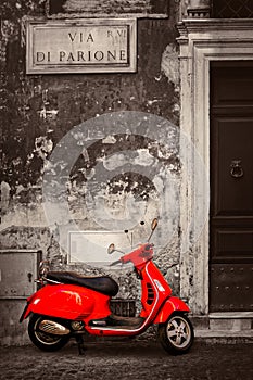 Black and white scene with a red scooter on a central Rome street