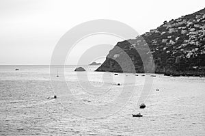 Black and white scenery of Tyrrhenian sea bay near Fiordo di Furore and Positano mountains region in Campania. Boats floating on