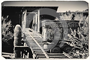 Black and White Sepia Vintage Photo of Goldfield Gold Mine`s old dangerous entrance to a gold mine shaft with trolley