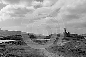 Black and white serene landscape with Ardvreck Castle ruins set against Scotland\'s rugged terrain