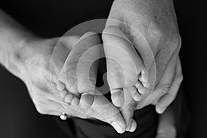 Black white shade beautiful shape hands of mother, hold tiny newborn baby feet