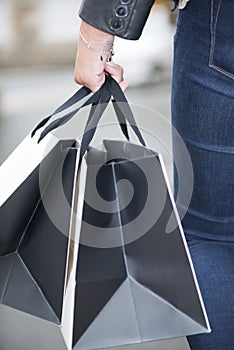 Black and white shopping bags holding by young adult female