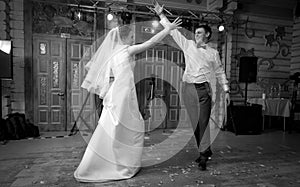 Black and white shot of bride and groom dancing at hall