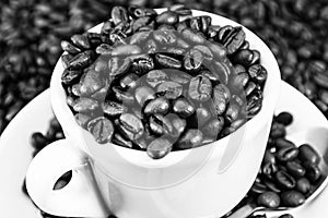 Black and white shot of a coffee cup full of coffee beans