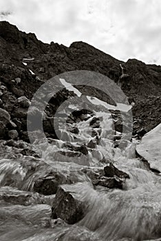 Black and white shot of a fast-flowing stream on rocky mountains
