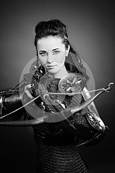 Black and white shot of a girl knight in armor and with weapons