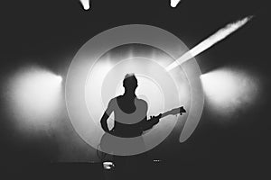 Black and white shot of guitarist silhouette in a stage backlights photo