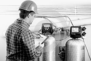 Black and white shot of inspector checking factory equipment