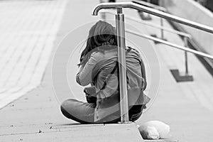 Black and white shot of a lonely woman sitting alone on a ground