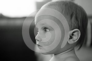 Black and white side portrait of little child. Closeup face with big pensive eyes. Baby portrait at home