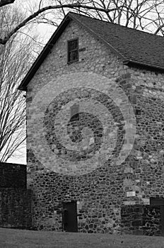 Black an white Side view of a large stone barn.