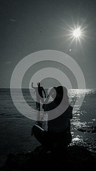 Black and white silhouette man and woman at the beach sea ocean in the morning