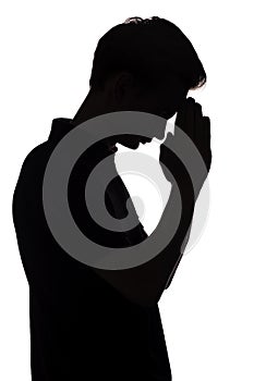 Black and white silhouette portrait of an unrecognizable man in stree, guy face profile dropping his head down and praying on a