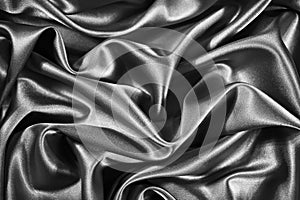 Black white silk satin background. Wavy soft folds on shiny fabric. Silver luxury background for design.