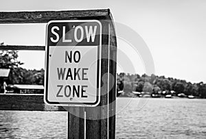 Black and White Slow No Wake sign on a lake