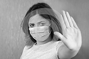 Black and white stop the virus and epidemic diseases. Healthy woman in blue medical protective mask showing gesture stop