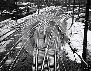 Black and white street photo with intertwining wires and railway tracks at a large railway station.