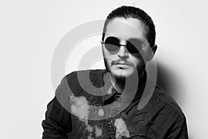 Black and white studio portrait of serious handsome man, wearing shades.