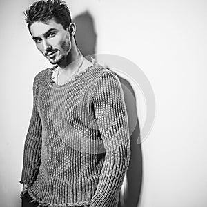 Black-white studio portrait of young handsome man in knitted sweater. Close-up photo.