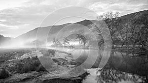 Black and white Stunning Autumn landscape sunrise image looking towards Borrowdale Valley from Manesty Park in Lake District with