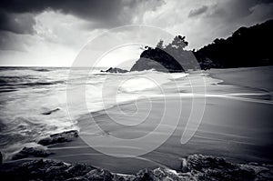 Black and white stunning white wave flow hitting the sandy beach