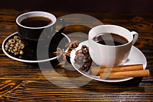 Black and white teacups with coffee and cinnamon