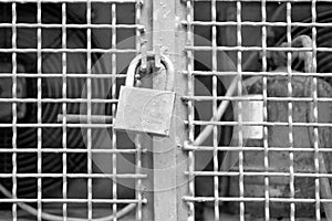 Black and white texture of metal grate with padlock