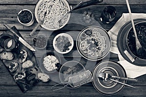Black and white.Traditional Italian food. Pasta spaghetti with tomato sauce, olives and garnish with wine on the wooden table. Nat