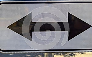 black and white traffic sign with arrows pointing to the left and to the right.