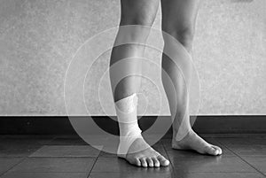 Black and white version of Athlete standing with an ankle tape job on their injured ankle