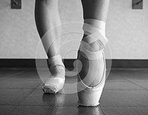 Black and white version of Close up view of a ballerina ballet dance, warming up her feet in ballet class