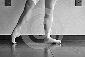 Black and white version of the hardworking disciplined ballerina ballet dancer warming up in her pointe shoes