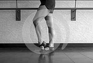 Black and white version of Jazz dance class, barre work foot in dig