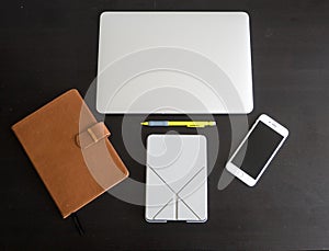 Black and white version of Student and worker desktop workspace layout including a laptop, smartphone, journal, tablet and pencil