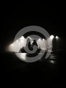 Black and white vertical night time scene with floodlights and dark sky