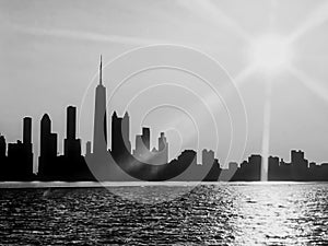 Black and White view of Chicago skyline seen from Lake Michigan, with sunset and sunbeams extending over cityscape during summer