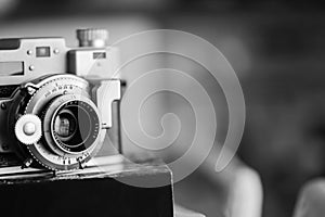 Black and white vintage old photography film camera with lens on a book. Close up shot