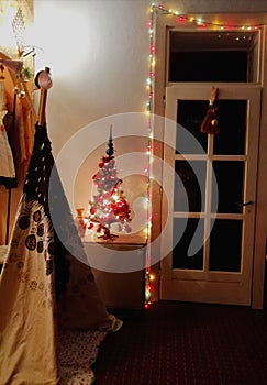 Black and white wigwam teepee kids tent standing in the living room with christmas tree and white glassy door.