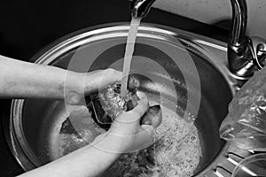 Black and white of a woman hand washes in a sink