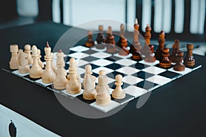 Black and white wooden chess set before the game on the chessboard.