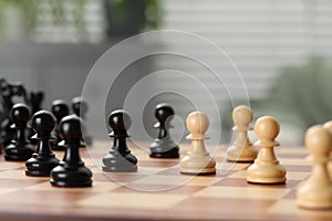 Black and white wooden pawns on chess board, closeup. Space for text