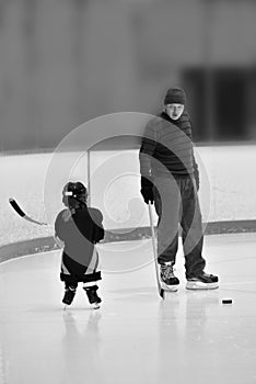 Black and whiteBlack and white photo of little hockey girl is wearing in full equipment: helmet, glows, skates, stick. She is hold