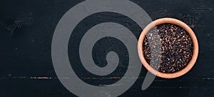 Black wild rice in a plate on a wooden background.
