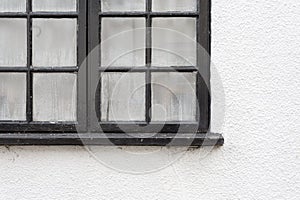 Black window frame with condensation drops on white painted cottage wall